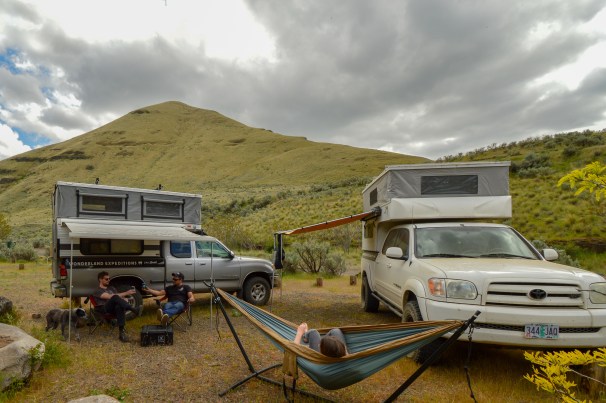 Trucks with slide in campers, dog, hammock, mountains, clouds, people